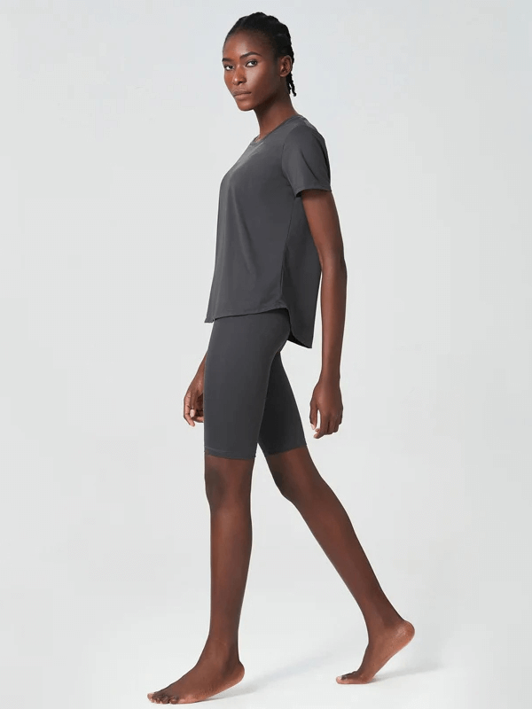 Woman wearing a black solid color two-piece yoga set with short sleeves, ideal for workouts and gym sessions.